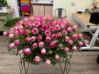 Bouquet of pink flowers in a metal stand on a wooden floor.