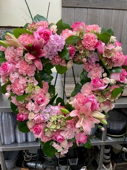 Floral wreath with pink flowers on a metal shelf.