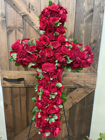 Floral cross made of red roses against a wooden background