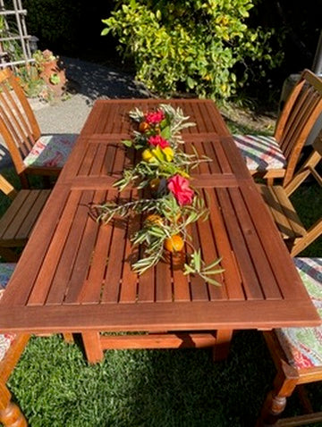 Wooden outdoor table with floral centerpiece in a garden setting