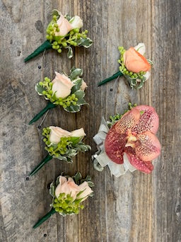 Set of floral boutonnieres on a wooden surface