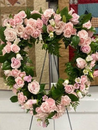 Floral wreath with pink and white flowers on a stand.
