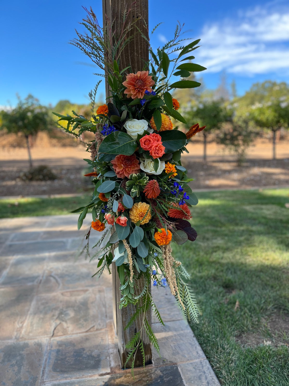 Decorative floral arrangement on a wooden post with a garden background
