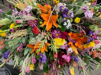 Colorful bouquet of flowers with various types of flowers including orange lilies and purple hydrangeas.