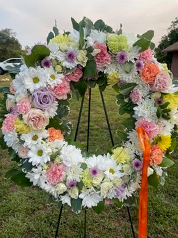 Circular-shaped floral arrangement with colorful flowers on a stand outdoors.