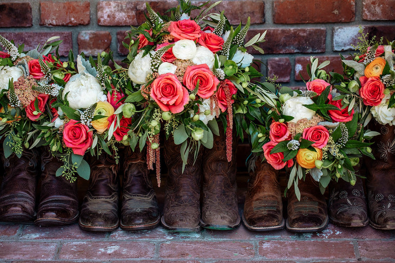 Decorative arrangement of boots with floral arrangements on a brick wall background